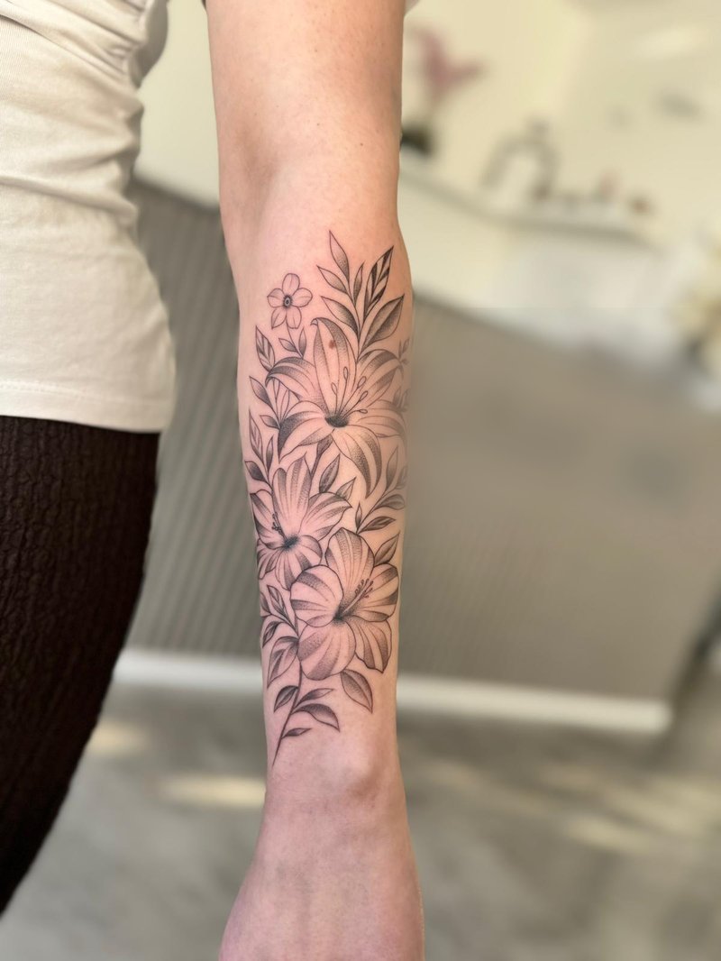 Florales Fineline-Tattoo mit Lilien am Unterarm