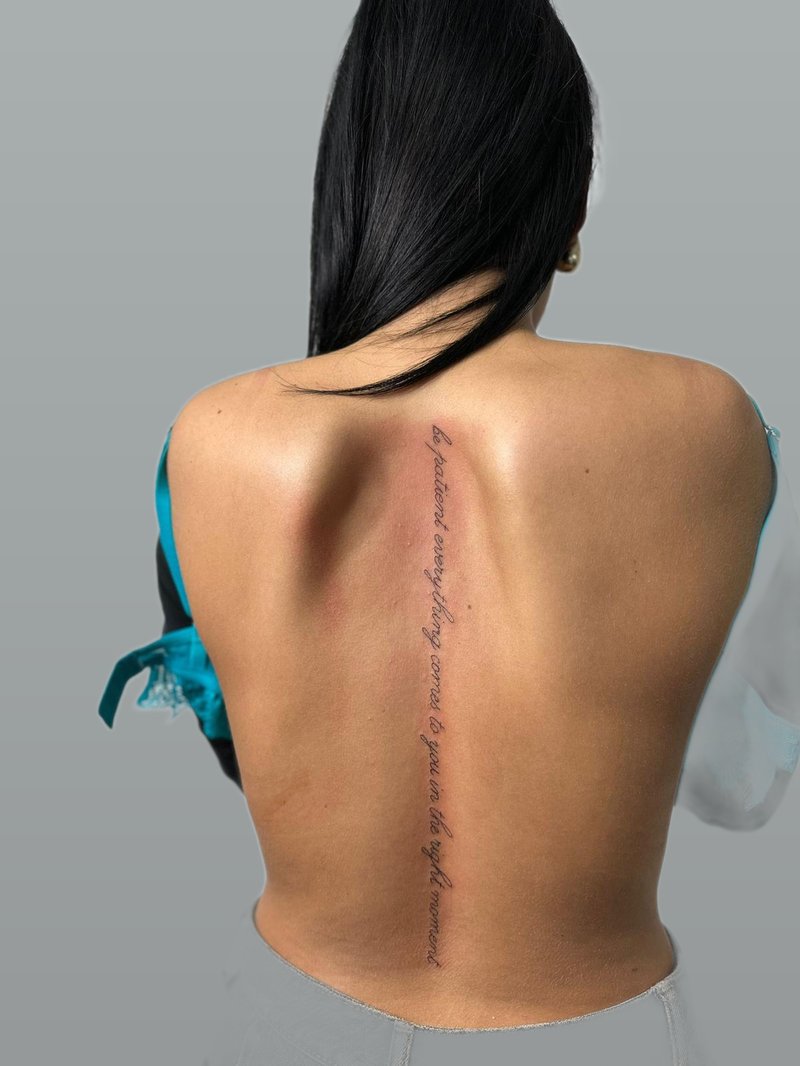 Feines Spine-Lettering entlang der Wirbelsäule – Fineline-Schriftzug-Tattoo